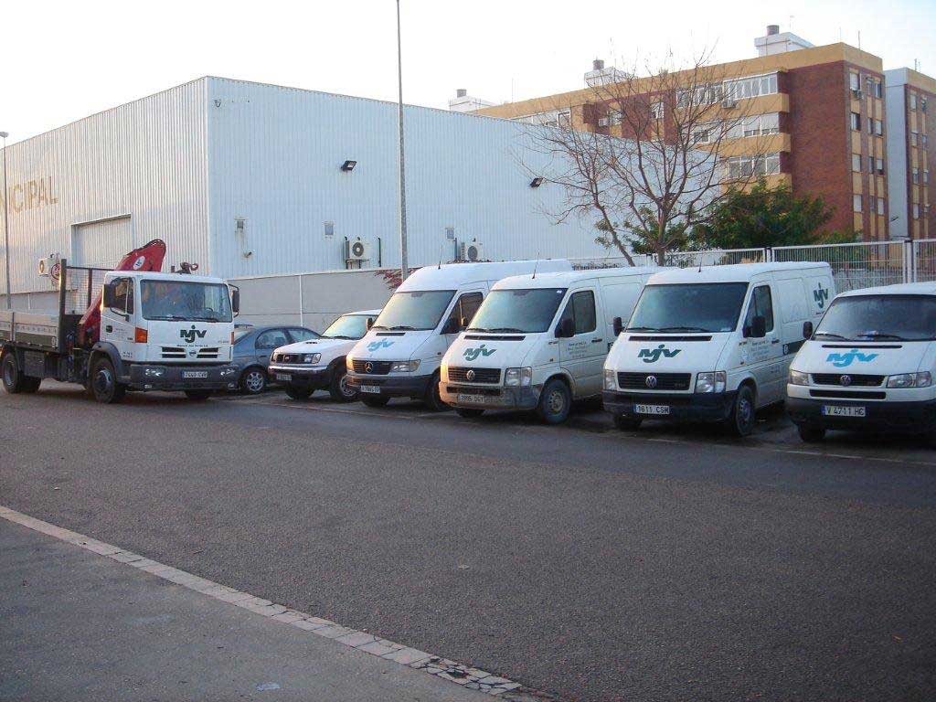 Flota de furgonetas y camión pluma de MJV frente a la nave